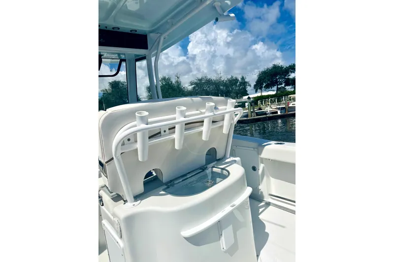 Slide: The Image of 2020 Sea Hunt Gamefish 27 boat interior with rod holders and seating, under a blue sky. - 10
