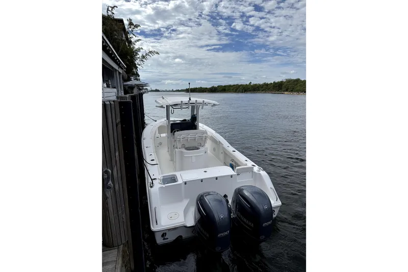 Slide: The Image of 2020 Sea Hunt Gamefish 27 boat docked by a serene river under a cloudy sky. - 4