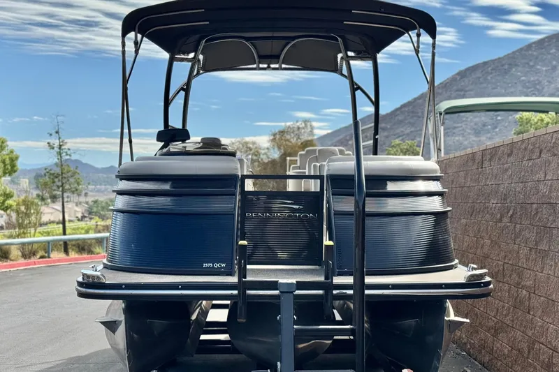 Slide: The Image of 2015 Bennington 2575 QCW pontoon boat with canopy, parked outdoors. - 2