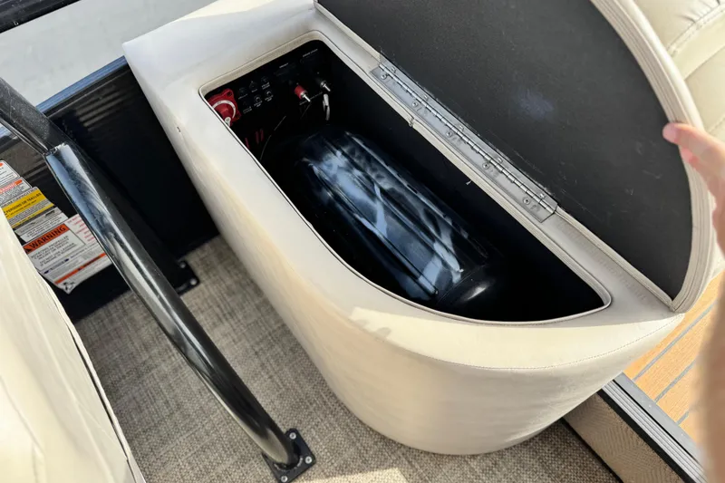 Slide: The Image of Storage compartment in a 2015 Bennington 2575 QCW boat, featuring a battery and control panel. - 21