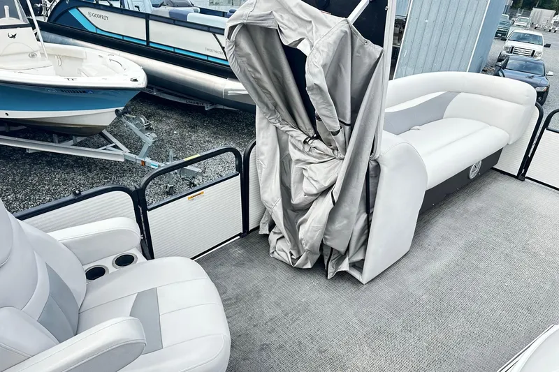 Slide: The Image of 2017 Godfrey Sweetwater 2286 Tri Toon interior with seating and cover, docked near other boats. - 12