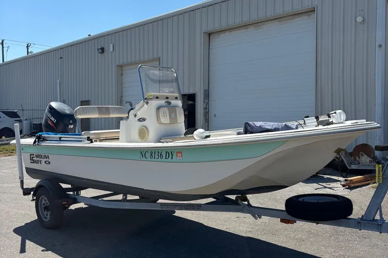 Slide: The Image of 2014 Carolina Skiff JVX18CC boat on trailer, parked outside a warehouse. - 0