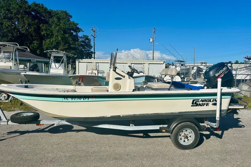 Slide: The Image of 2014 Carolina Skiff JVX18CC boat on trailer, parked outdoors under clear blue sky. - 1