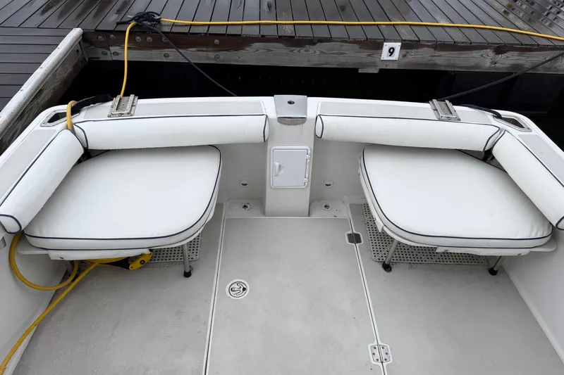 Slide: The Image of 2005 Back Cove 26 boat interior with white cushioned seating and dock view. - 14