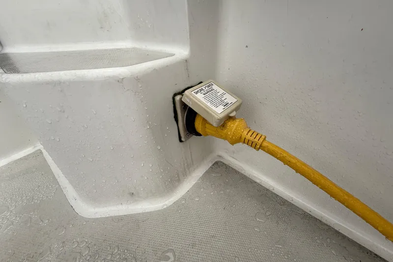 Slide: The Image of Yellow shore power cable connected to a 2005 Back Cove 26 boat, with visible water droplets. - 19