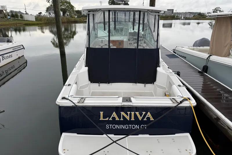 Slide: The Image of 2005 Back Cove 26 boat docked, rear view with canopy and "LANIVA" name. - 2