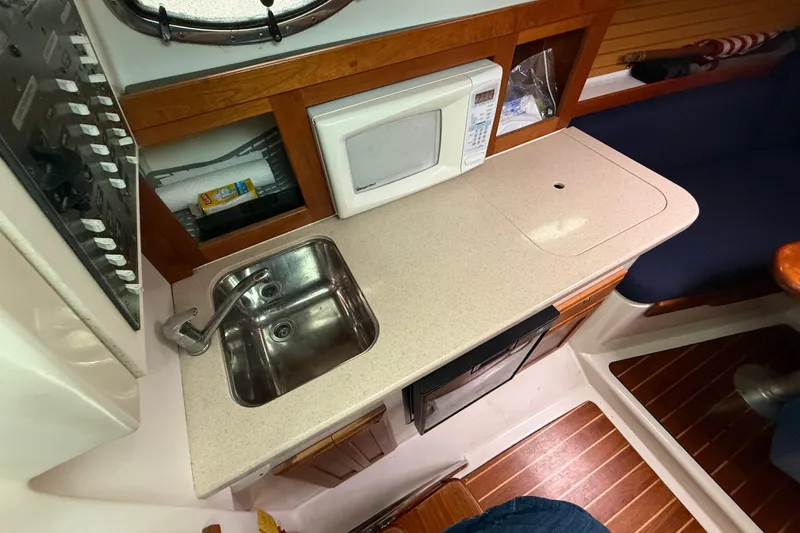 Slide: The Image of 2005 Back Cove 26 boat galley with sink, microwave, and wooden cabinetry. - 45