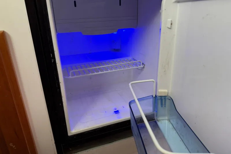 Slide: The Image of Open refrigerator with blue interior light in a 2005 Back Cove 26 boat. - 52
