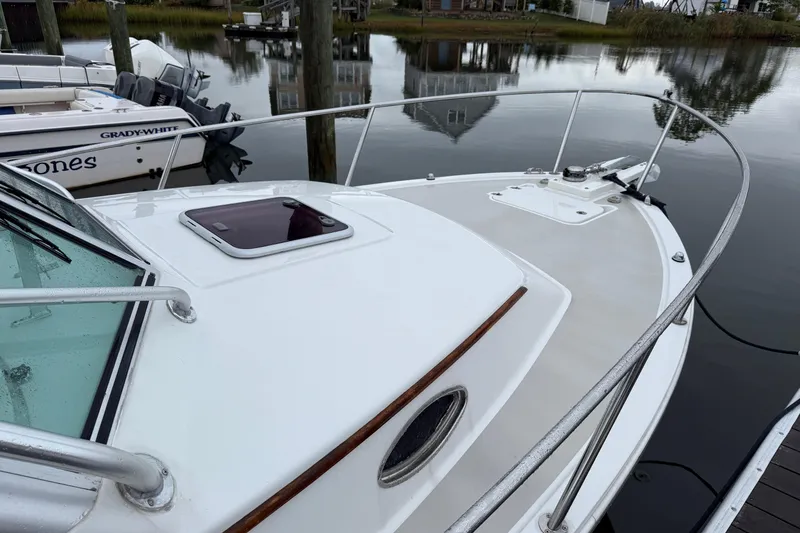 Slide: The Image of 2005 Back Cove 26 boat docked, featuring sleek white deck and railing. - 6
