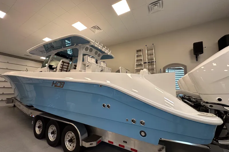 Slide: The Image of 2025 HCB 42 Lujo boat in showroom, featuring sleek blue and white design on trailer. - 40