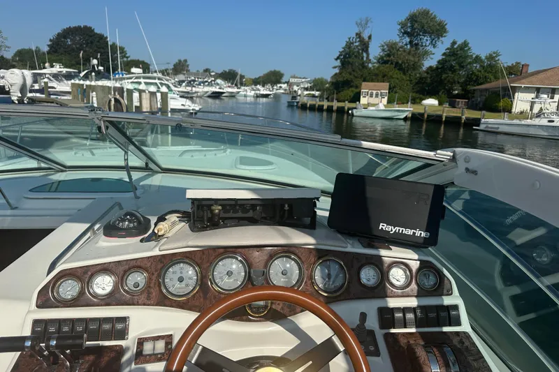 Slide: The Image of 2000 Doral 360 SE boat interior with curved seating and table by the water. - 9