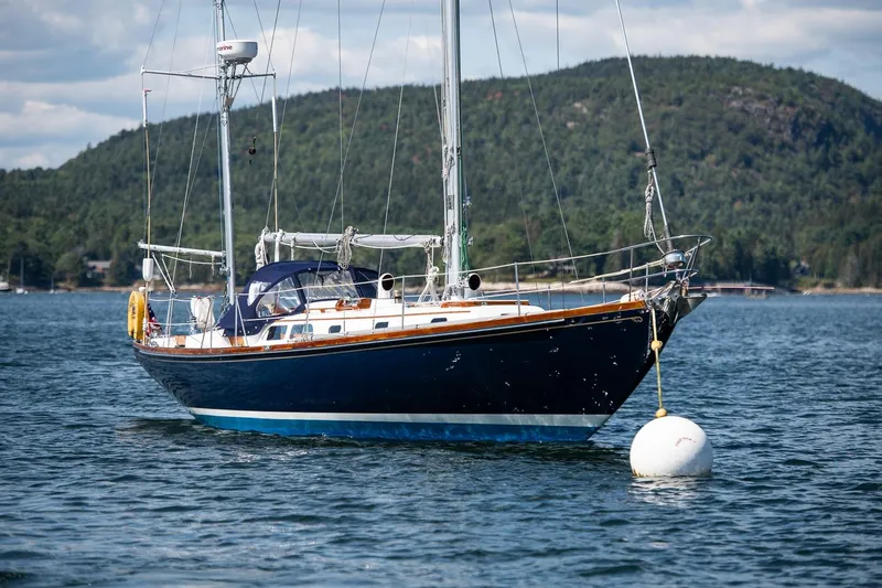 Slide: The Image of 1971 Hinckley Bermuda 40 Custom Yawl anchored on scenic water with hills in background. - 1