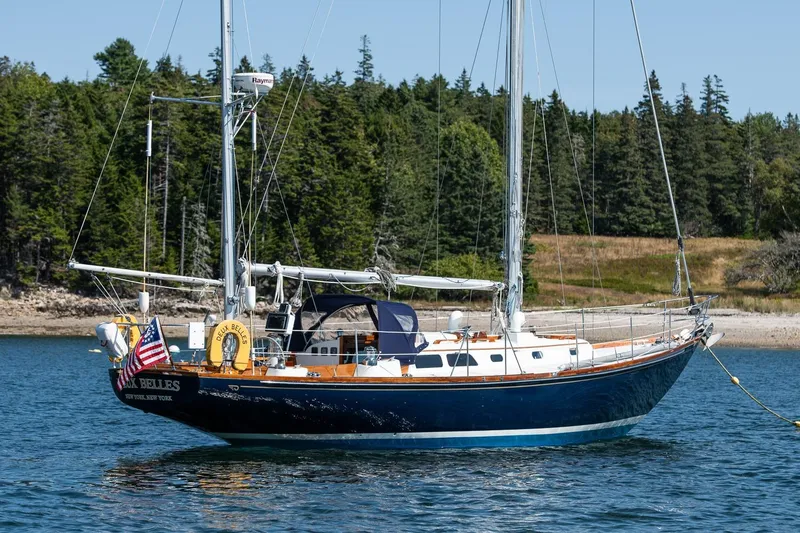 Slide: The Image of 1971 Hinckley Bermuda 40 Custom Yawl sailing on calm waters near a forested shoreline. - 6