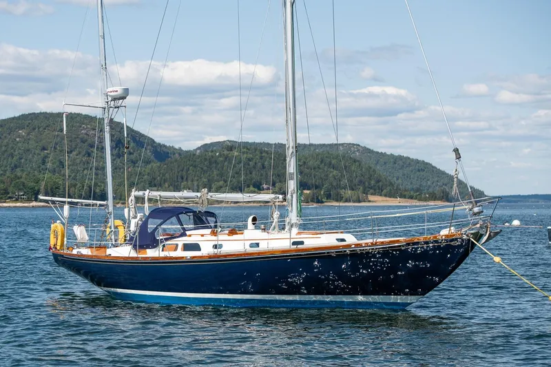 The Image of 1971 Hinckley Bermuda 40 Custom Yawl sailing on a serene lake with forested hills. - 0