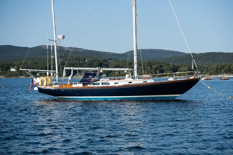 Slide: The Image of 1971 Hinckley Bermuda 40 Custom Yawl sailing on serene waters with scenic mountain backdrop. - 7