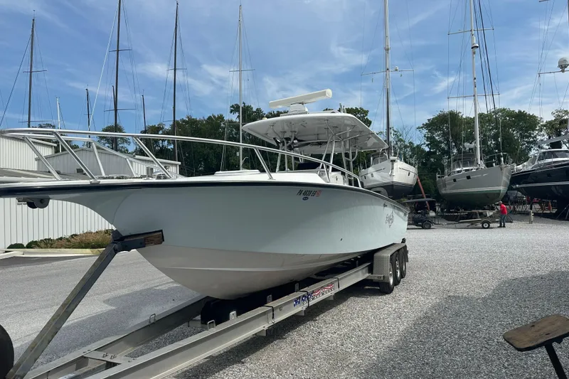 Slide: The Image of 1999 Jupiter 31 Cuddy boat on trailer in marina with sailboats in background. - 10