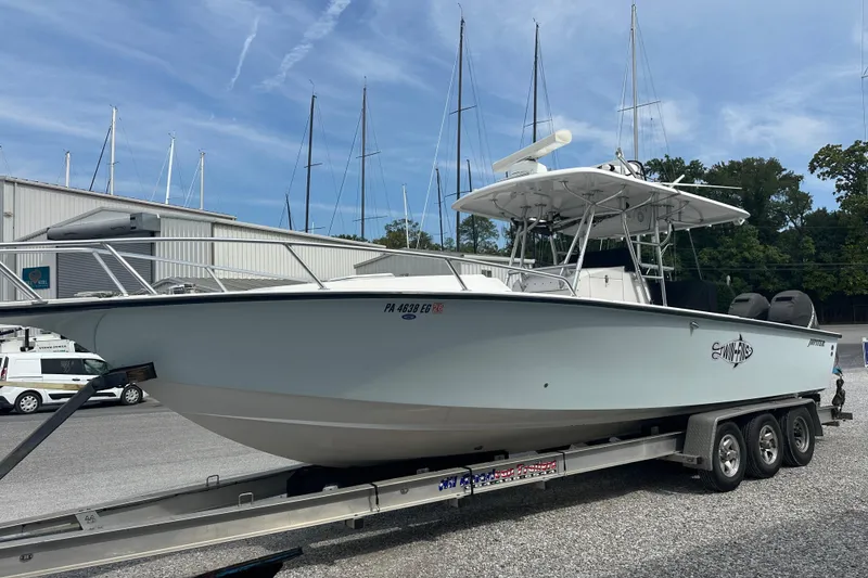 Slide: The Image of 1999 Jupiter 31 Cuddy boat on trailer, parked at marina with sailboats in background. - 16