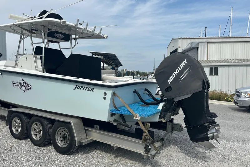 Slide: The Image of 1999 Jupiter 31 Cuddy boat on trailer with Mercury outboard motor, parked near marina. - 17