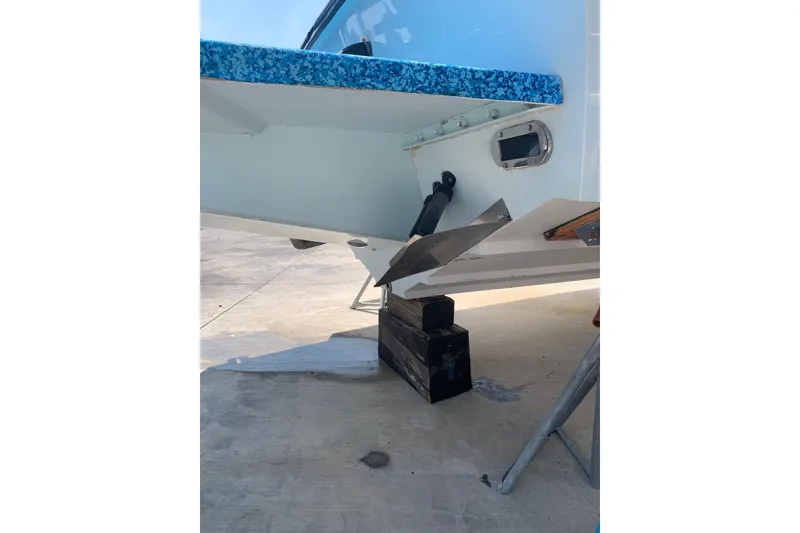 Slide: The Image of 1999 Jupiter 31 Cuddy boat stern view on blocks, showcasing trim tab and hull details. - 4