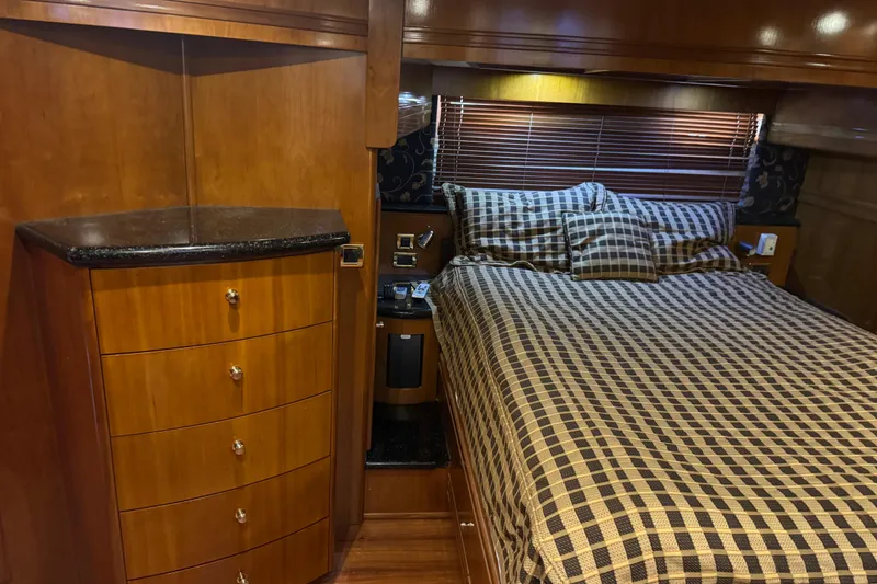 Slide: The Image of Luxurious 2001 Carver 530 Voyager Pilothouse bedroom with wood cabinetry and checkered bedding. - 29