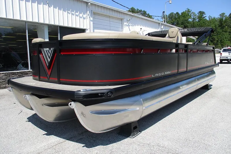 Slide: The Image of 2025 Viaggio Lago X22U pontoon boat with sleek black and red design, parked outdoors. - 3