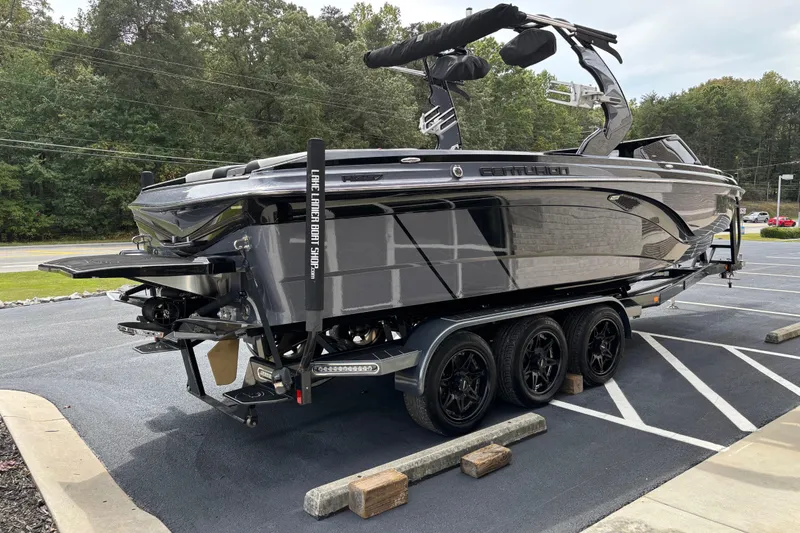 Slide: The Image of 2018 Centurion Ri257 boat on trailer in parking lot, surrounded by trees. - 3
