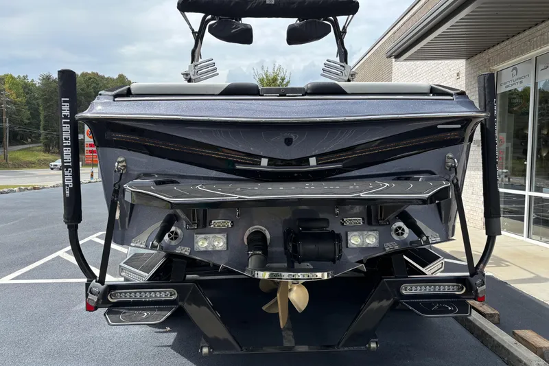 Slide: The Image of 2018 Centurion Ri257 boat rear view, showcasing propeller and swim platform in a parking lot. - 4