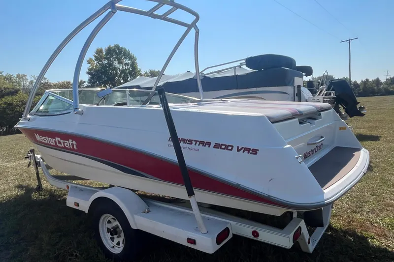 Slide: The Image of 1996 MasterCraft MariStar 210 VRS boat on trailer, white with red accents, parked outdoors. - 2