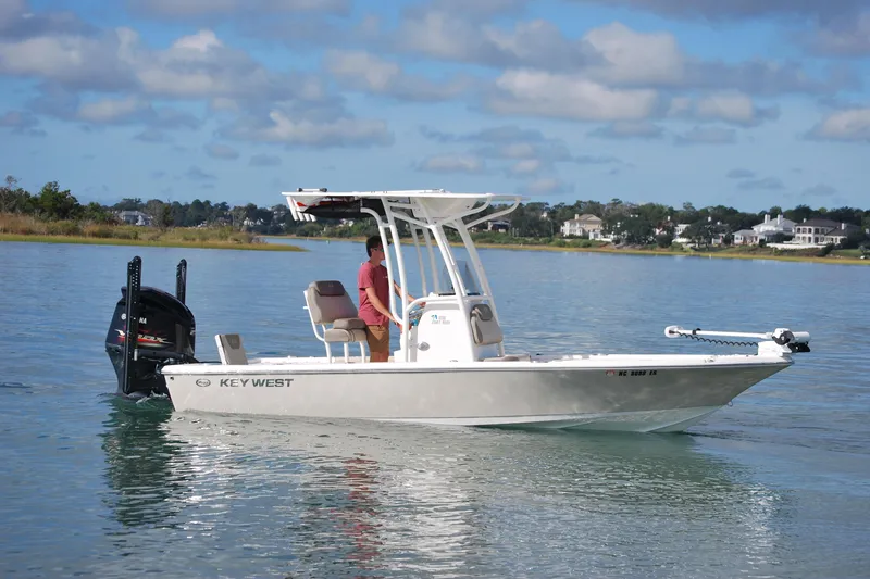 Slide: The Image of 2021 Key West 210 Bay Reef boat on calm water, with a person steering. - 5