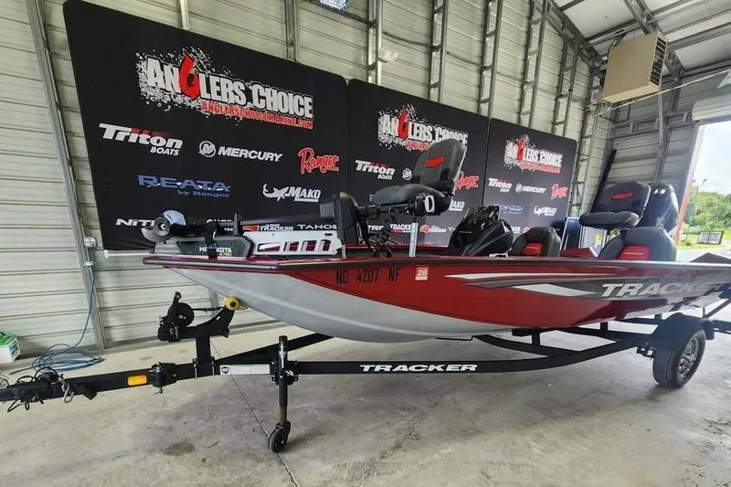 Slide: The Image of 2025 Tracker Pro Team 175 boat on trailer in showroom with promotional banners. - 3