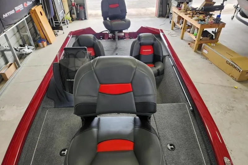 Slide: The Image of 2025 Tracker Pro Team 175 boat interior with red and black seating in a garage. - 8