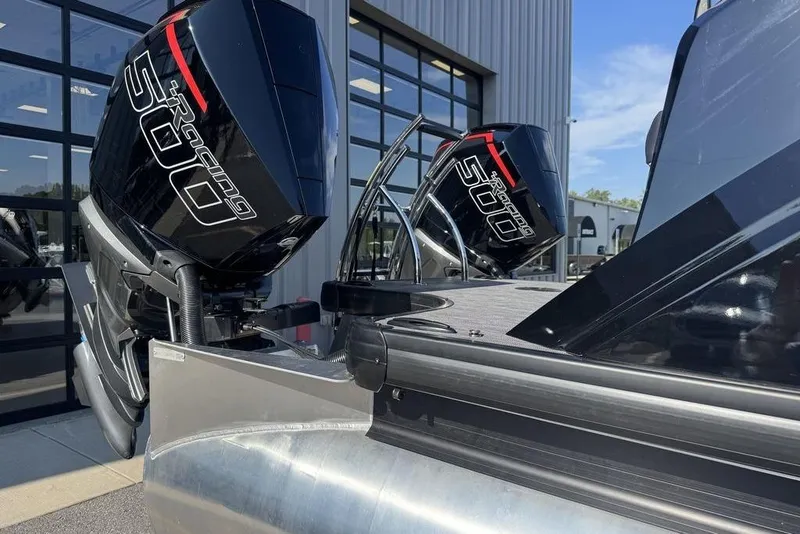 Slide: The Image of Twin outboard engines on a 2026 Godfrey XP 2700 TWIN boat, parked near a building. - 2