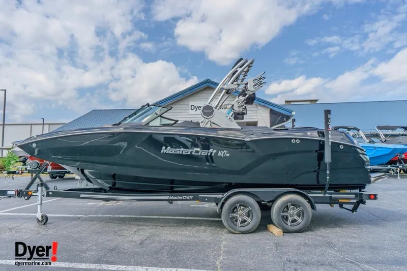 The Image of 2026 MasterCraft NXT22 boat on trailer at dealership, under a blue sky. - 1