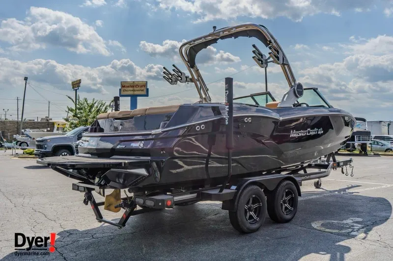 Slide: The Image of 2026 MasterCraft NXT22 boat on trailer in parking lot under cloudy sky. - 5