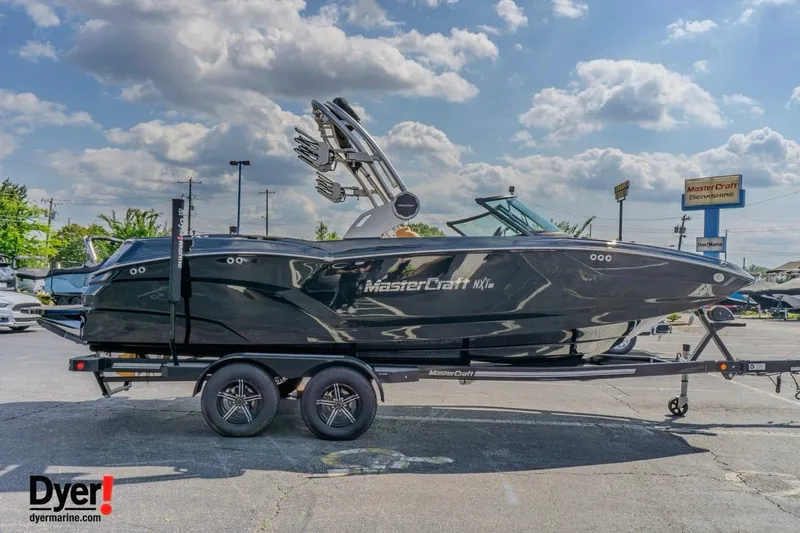 Slide: The Image of 2026 MasterCraft NXT22 boat on trailer under a cloudy sky at dealership. - 6