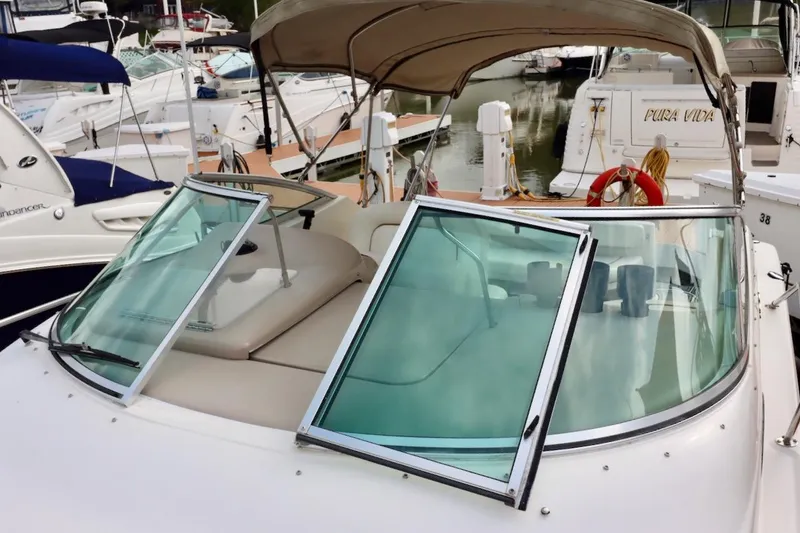 Slide: The Image of 2000 Sea Ray 270 Sundancer boat docked, featuring open windshield and beige canopy. - 11