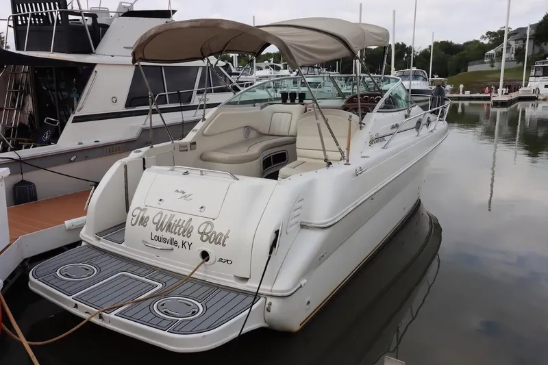 Slide: The Image of 2000 Sea Ray 270 Sundancer boat docked, featuring beige seating and canopy. - 2