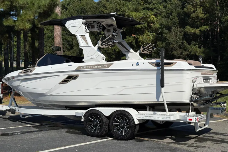Slide: The Image of 2025 Centurion Ri245 boat on trailer, parked outdoors, surrounded by trees. - 10