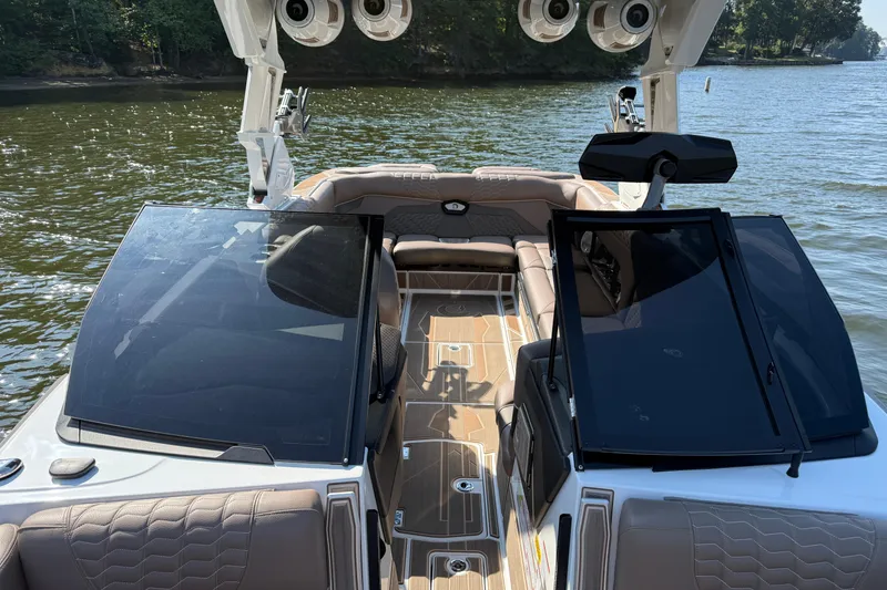 Slide: The Image of 2025 Centurion Ri245 boat interior with open windshield, on a calm lake. - 16