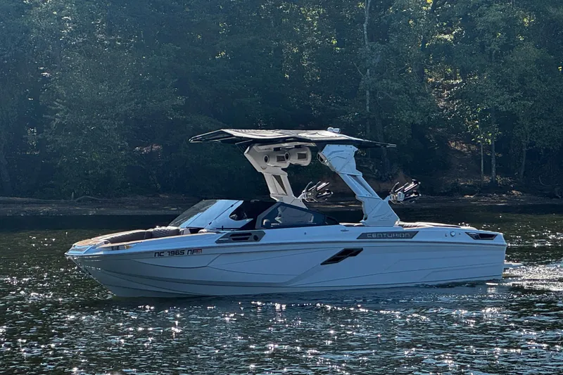 Slide: The Image of 2025 Centurion Ri245 boat cruising on a serene lake with lush forest backdrop. - 3