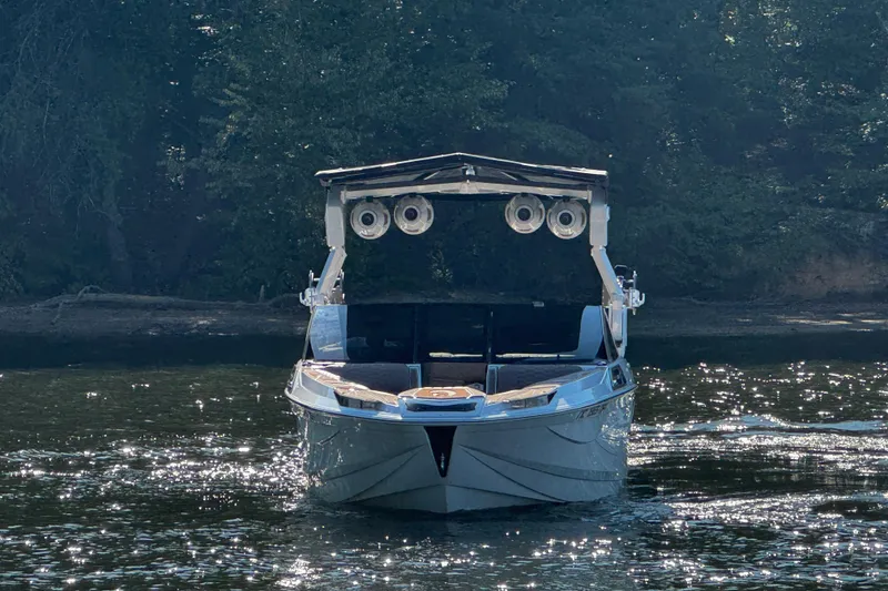 Slide: The Image of 2025 Centurion Ri245 boat on a sunlit lake with forest backdrop. - 4