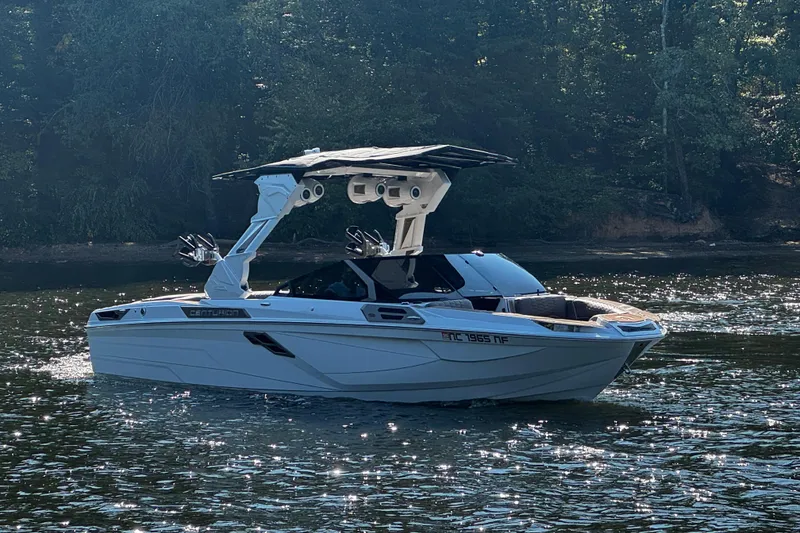 Slide: The Image of 2025 Centurion Ri245 boat on a sunlit lake with forested background. - 5