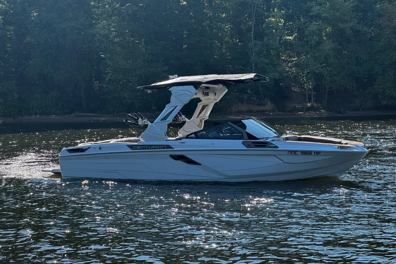 Slide: The Image of 2025 Centurion Ri245 boat on a serene lake with lush forest backdrop. - 6