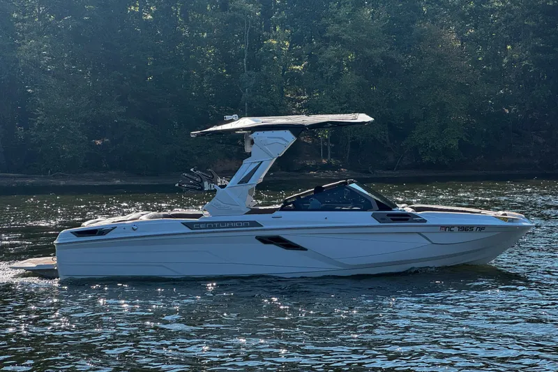 Slide: The Image of 2025 Centurion Ri245 boat cruising on a sunlit lake with forest backdrop. - 7