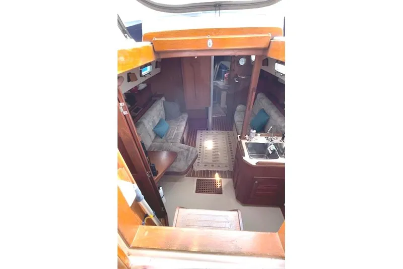 Slide: The Image of Interior of 1997 Island Packet 37 sailboat, featuring cozy seating and wooden finishes. - 12