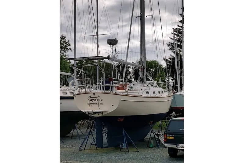 Slide: The Image of 1997 Island Packet 37 sailboat on stands, overcast sky, surrounded by trees and vehicles. - 13