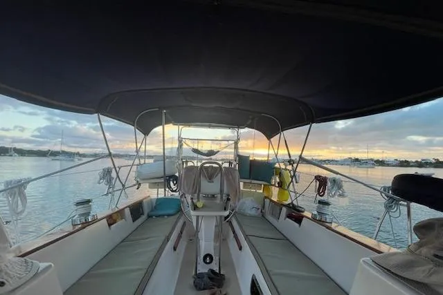 Slide: The Image of 1997 Island Packet 37 sailboat cockpit at sunset, calm waters, and moored boats in the background. - 3