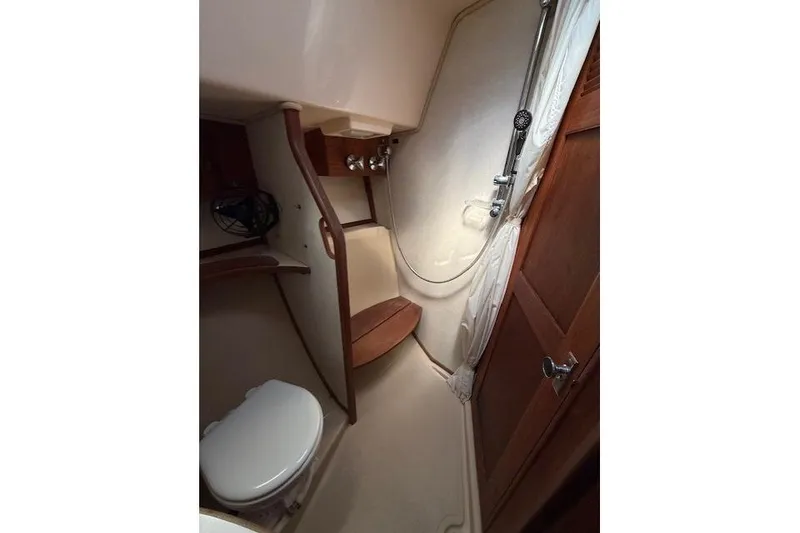 Slide: The Image of 1997 Island Packet 37 yacht bathroom with shower, toilet, and wooden accents. - 5