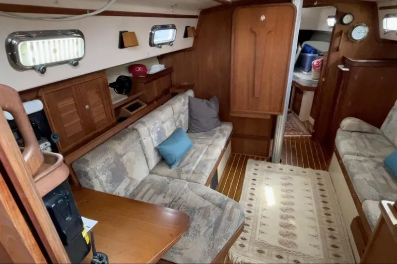 Slide: The Image of Interior of a 1997 Island Packet 37 sailboat with cozy seating and wooden accents. - 8