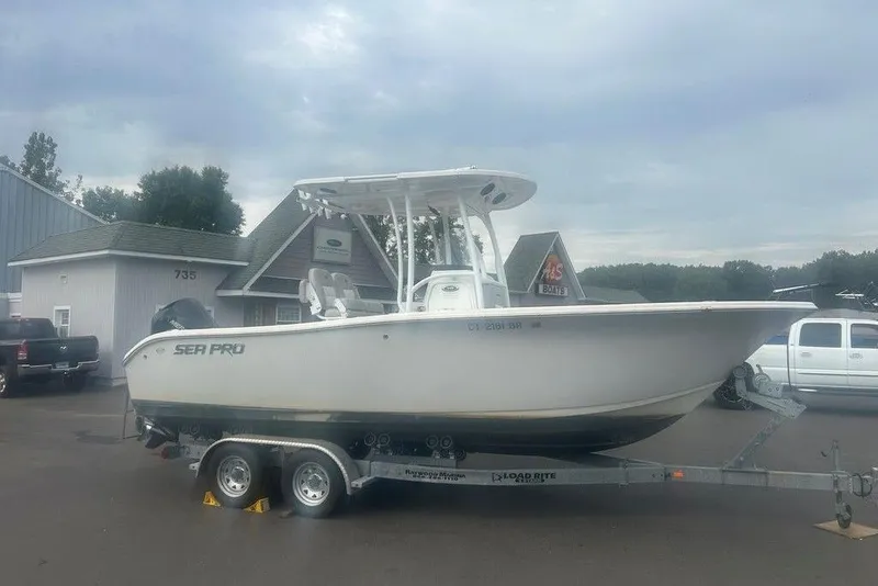 Slide: The Image of 2019 Sea Pro 219 boat on trailer, parked outside a building under cloudy sky. - 2